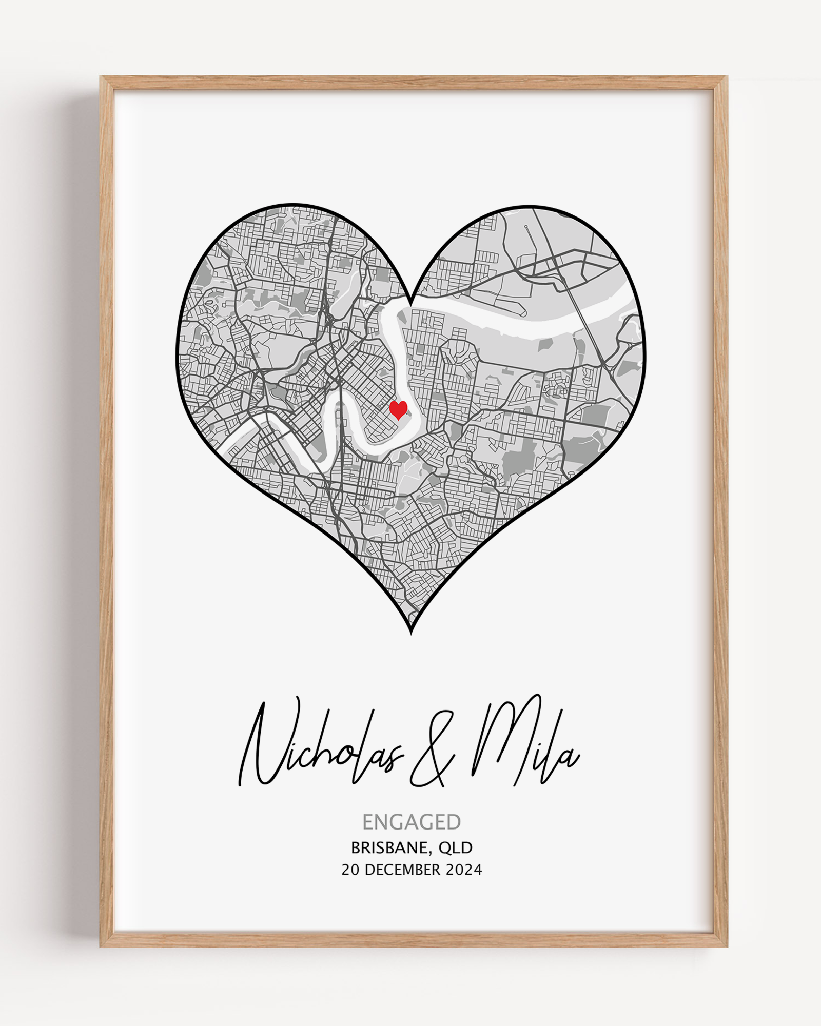 Heart-shaped engagement map print with a red heart marking the proposal location, customized with couple’s names and date in elegant script below the map on a white background.