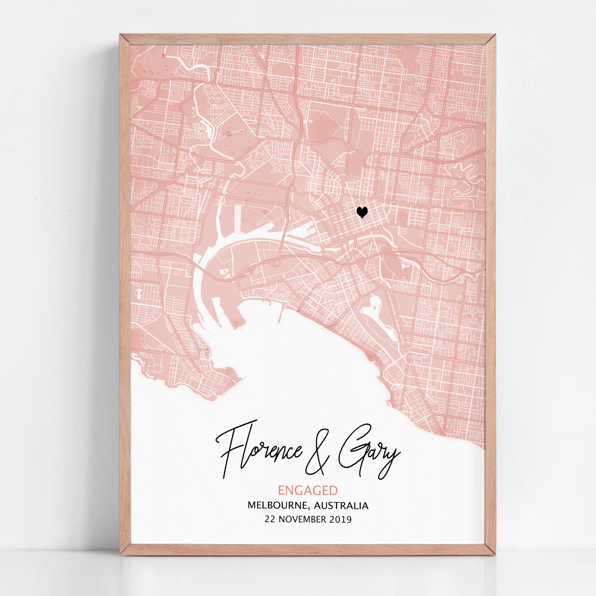 Modern pastel colour map print with light grey streets and a red heart marking a special location, customized with couple’s names and engagement date in elegant script below.