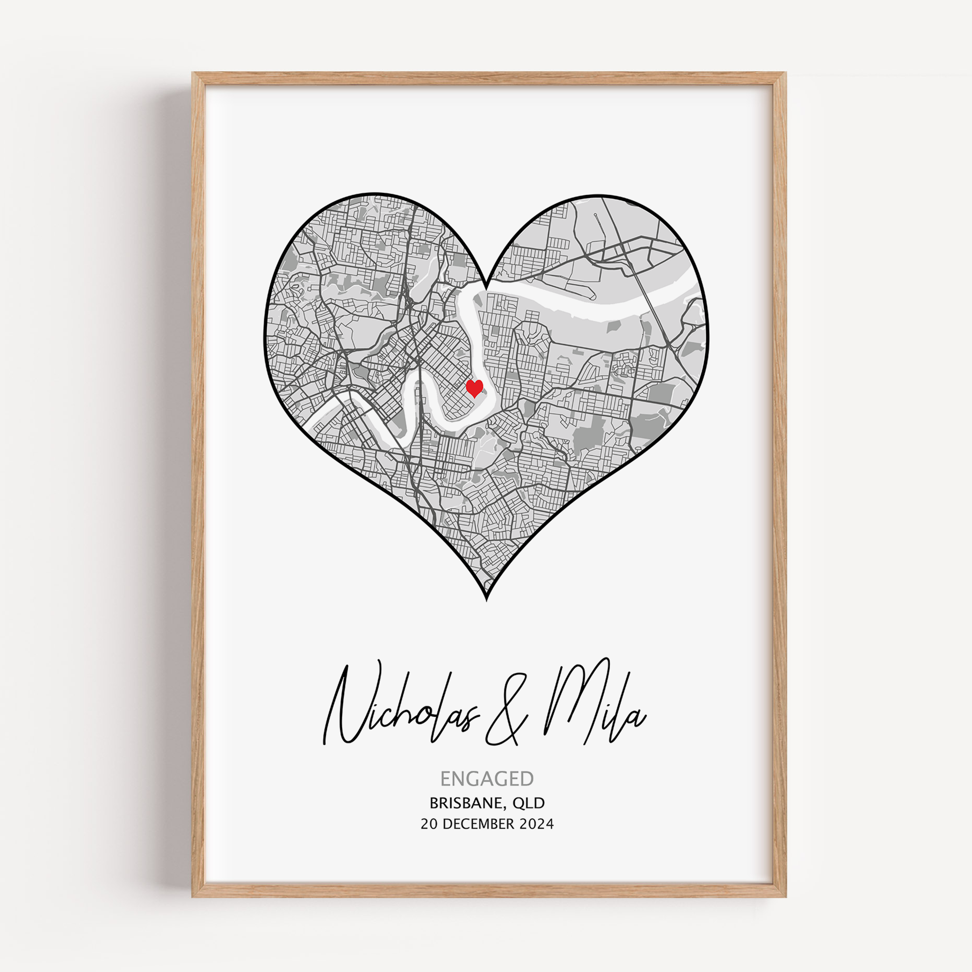 Heart-shaped engagement map print with a red heart marking the proposal location, customized with couple’s names and date in elegant script below the map on a white background.